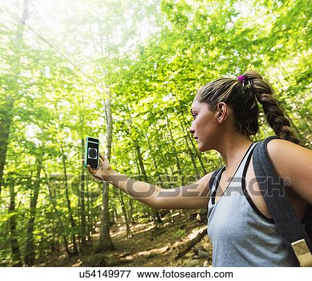 Stock Photo - Female hiker looking at compass on phone. Fotosearch
