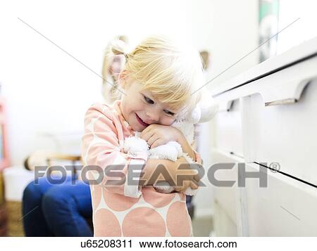 Stock Image - Girl (2-3) embracing toy. Fotosearch