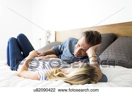 Husband lying down on bed with pregnant wife View Large Photo Image Stock Image - Husband lying down on bed with pregnant wife. Fotosearch