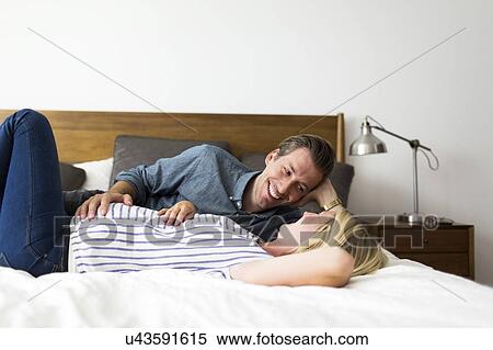 Husband lying down on bed with pregnant wife View Large Photo Image Stock Photography - Husband lying down on bed with pregnant wife. Fotosearch
