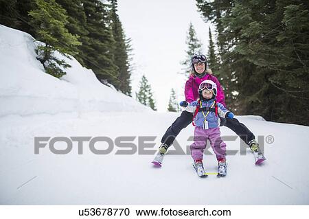 Stock Image - Little girl (2-3) learning skiing with mother. Fotosearch