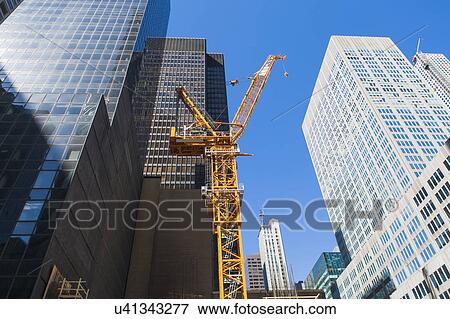 Low angle view of crane among skyscrapers View Large Photo Image Stock Photo - Low angle view of crane among skyscrapers . Fotosearch