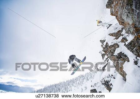 Stock Photo - Low angle view of two men jumping from ski slope. Fotosearch