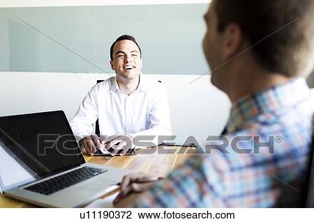 Stock Image - Man being interviewed in conference room. Fotosearch