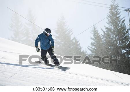 Stock Image - Man snowboarding downhill. Fotosearch