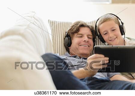 Man using tablet pc with his son (8-9) on sofa View Large Photo Image Stock Image - Man using tablet pc with his son (8-9) on sofa. Fotosearch