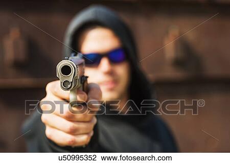 Stock Image - Man with handgun pointing towards camera. Fotosearch