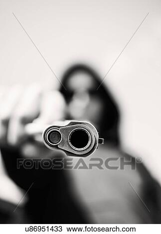 Stock Image - Man with handgun pointing towards camera. Fotosearch