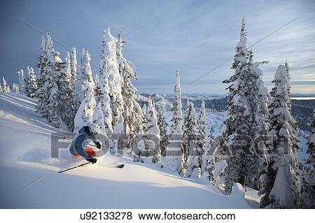 Stock Photo - Mature man on ski slope at sunset. Fotosearch