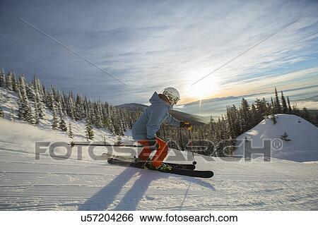 Stock Photograph - Mature man on ski slope at sunset. Fotosearch