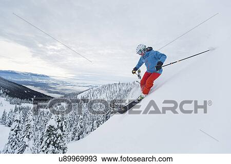 Stock Image - Mature man speeding on ski slope. Fotosearch