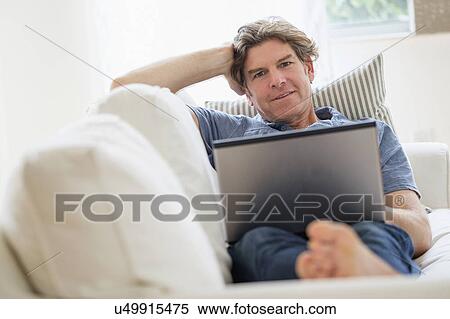 Mature man using laptop on sofa View Large Photo Image Stock Photography - Mature man using laptop on sofa. Fotosearch