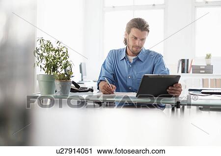 Mid-adult businessman working in office View Large Photo Image Stock Image - Mid-adult businessman working in office. Fotosearch