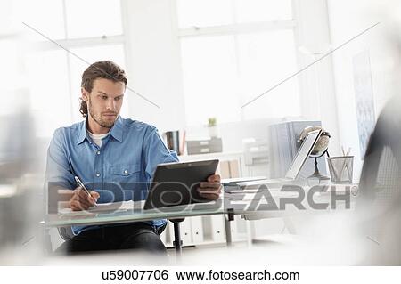 Stock Photograph - Mid-adult businessman working in office. Fotosearch