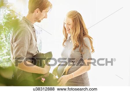 Stock Photo - Mid-adult couple playing with dog. Fotosearch