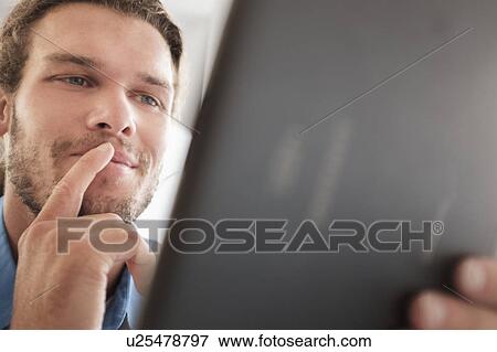 Stock Photo - Mid-adult man using tablet pc. Fotosearch