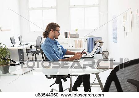 Mid-adult man working in office View Large Photo Image Stock Image - Mid-adult man working in office. Fotosearch
