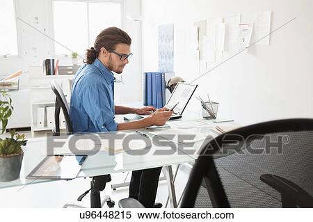 Stock Photography - Mid-adult man working in office. Fotosearch