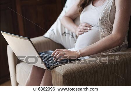 Mid-section of pregnant woman using laptop View Large Photo Image Stock Photograph - Mid-section of pregnant woman using laptop. Fotosearch