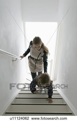 Stock Image - Mother and son (4-5) walking up stairs. Fotosearch