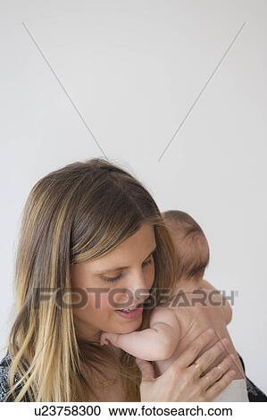 Stock Image - Mother holding baby girl (2-5 months) in her arms. Fotosearch