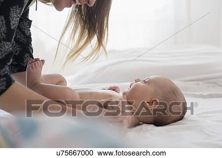 Mother playing with baby girl (2-5 months) on bed View Large Photo Image Stock Image - Mother playing with baby girl (2-5 months) on bed. Fotosearch