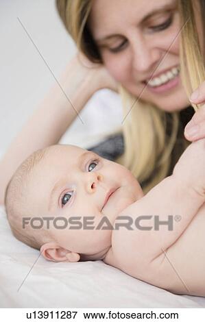 Mother playing with baby girl (2-5 months) on bed View Large Photo Image Stock Photo - Mother playing with baby girl (2-5 months) on bed. Fotosearch