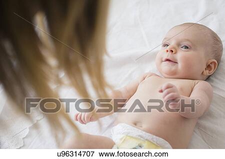 Mother playing with baby girl (2-5 months) on bed View Large Photo Image Stock Photo - Mother playing with baby girl (2-5 months) on bed. Fotosearch