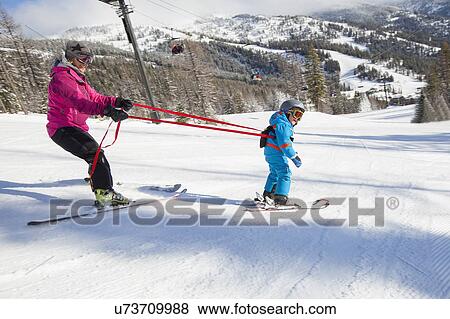 Stock Photo - Mother teaching son (4-5) how to ski. Fotosearch