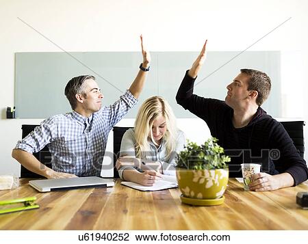 Stock Image - Office workers witting and working at desk. Fotosearch