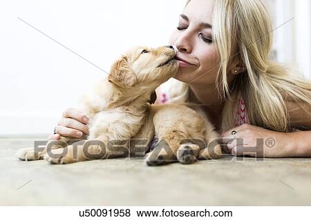 Stock Photo - Owner kissing Golden Retriever puppy . Fotosearch