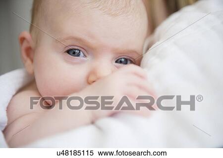 Stock Photography - Portrait of baby girl (2-5 months) in mother's arms. Fotosearch