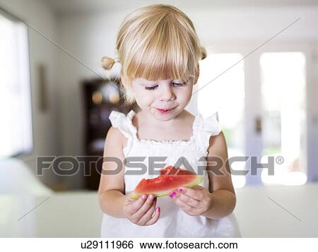 Stock Photograph - Portrait of girl (2-3) eating watermelon. Fotosearch
