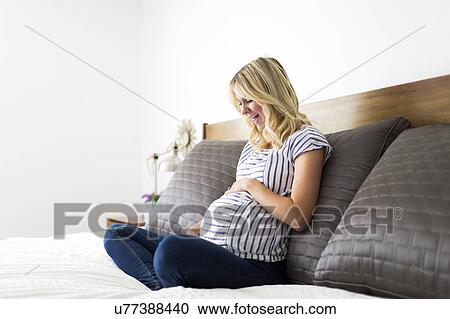 Stock Image - Portrait of pregnant woman touching belly. Fotosearch
