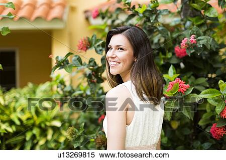 Stock Photography - Portrait of woman against blooming bush. Fotosearch