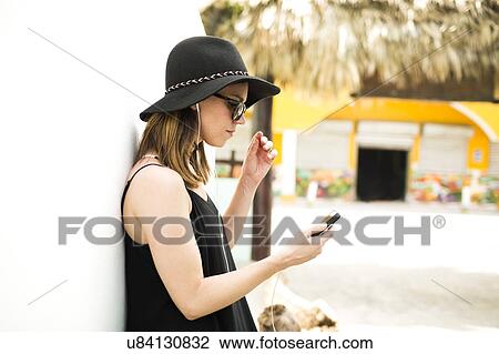 Stock Image - Portrait of woman wearing hat and sunglasses. Fotosearch