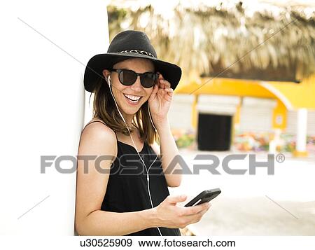 Stock Photo - Portrait of woman wearing hat and sunglasses. Fotosearch