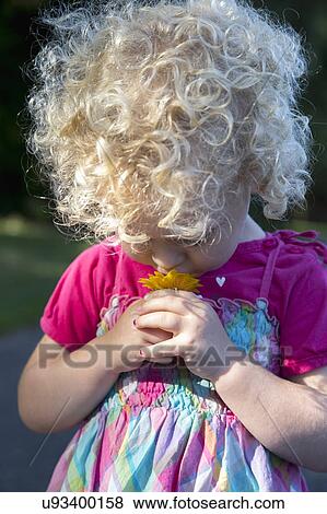 Stock Photo - Portrait of young girl (4-5) smelling flower. Fotosearch