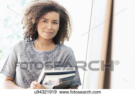 Stock Photo - Portrait of young woman holding books. Fotosearch