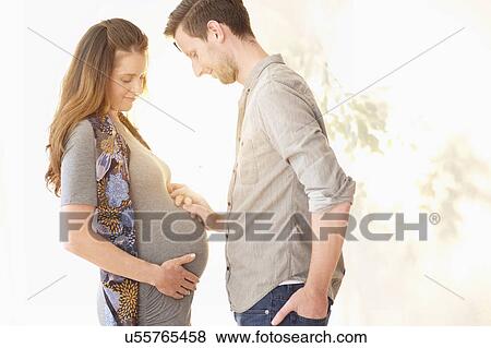 Stock Photo - Pregnant woman holding hands with her boyfriend. Fotosearch