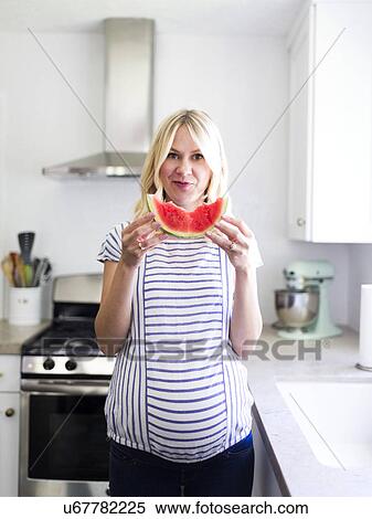 Stock Photography - Pregnant woman holding slice of watermelon . Fotosearch
