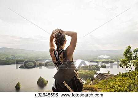 Stock Photograph - Rear view of young woman looking at lake. Fotosearch