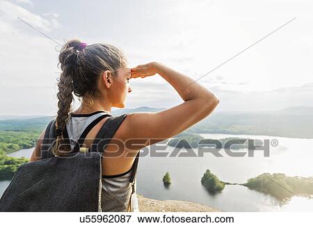 Rear view of young woman looking at view of lake View Large Photo Image Stock Photo - Rear view of young woman looking at view of lake. Fotosearch