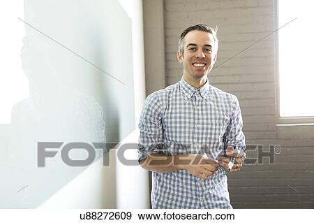 Smiling man standing next to whiteboard View Large Photo Image Stock Photo - Smiling man standing next to whiteboard. Fotosearch