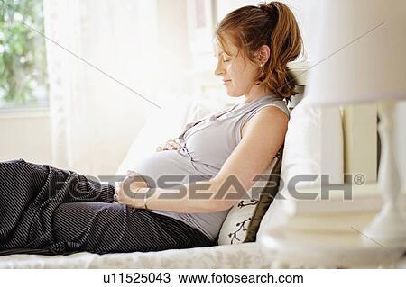 Smiling pregnant woman sitting on bed View Large Photo Image Stock Image - Smiling pregnant woman sitting on bed. Fotosearch