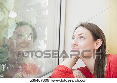 Smiling woman looking through window View Large Photo Image Stock Photo - Smiling woman looking through window. Fotosearch