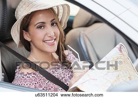 Picture - Smiling woman with map in car. Fotosearch
