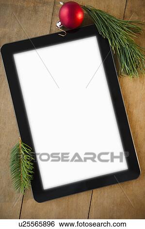 Stock Photograph - Studio shot of blank tablet and Christmas decoration on wood. Fotosearch