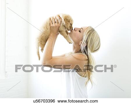 Studio shot of owner kissing Golden Retriever puppy View Large Photo Image Stock Photograph - Studio shot of owner kissing Golden Retriever puppy . Fotosearch