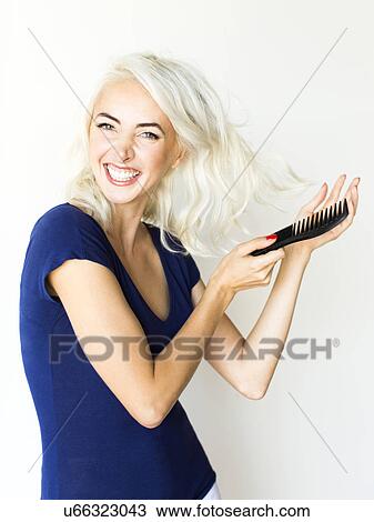 Studio shot of woman combing hair View Large Photo Image Stock Image - Studio shot of woman combing hair. Fotosearch